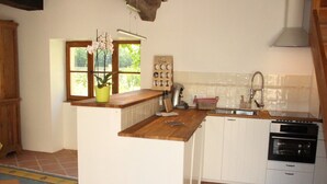 A kitchen with a wooden countertop, white cabinets, a sink, and an oven. - Elegant Family Home in Bouix (Bouix)