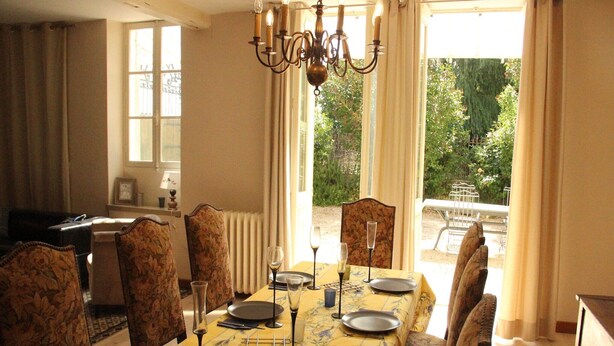 A dining room with a table set for four, chairs, a chandelier, and a view of the outdoors. - Elegant Family Home in Bouix (Bouix)