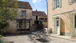 A courtyard with a table and chairs, surrounded by buildings with traditional architecture. - Elegant Family Home in Bouix (Bouix)