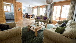 Un amplio espacio de sala con sofá, sillones, una mesa de centro y una mesa de comedor.