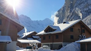 Un pueblo cubierto de nieve en la montaña, con casas de madera y un cielo despejado.