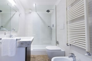 A modern bathroom with a glass-enclosed shower, a sink with a towel, and a toilet.