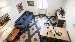 A compact living space with a sofa, a dining table with chairs, a radiator, and a window. - Nice Apartment Navona Square (Rome)
