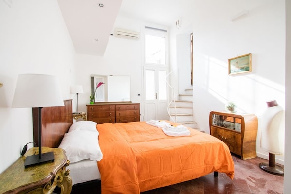 A bedroom with a bed, a dresser, a chair, a lamp, a mirror, and a window.