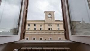 A view through a window of a building with a clock tower, a radiator, and a window frame. - Nice Apartment Navona Square (Rome)