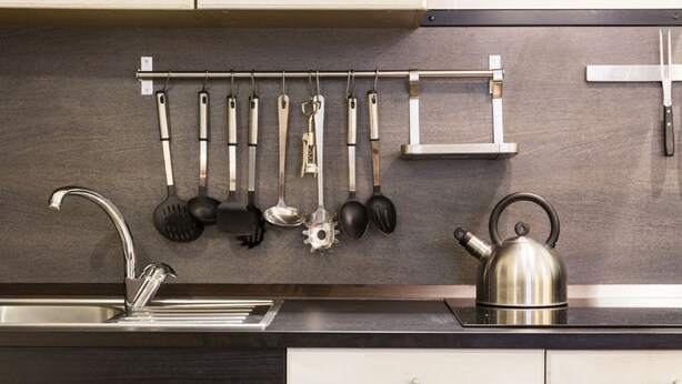 A kitchen with a stainless steel kettle, a hanging utensil rack, and a modern faucet. - Nice Apartment Navona Square (Rome)