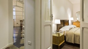 A hotel room with a bed, bedside lamps, a nightstand, and a wooden dresser. - Nice Apartment Navona Square (Rome)