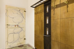 A room with a marble-patterned door, a wooden wardrobe with multiple compartments, and a metal shelf.