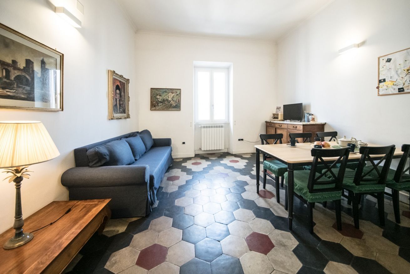 Een kamer met een bank, een eettafel met stoelen, een lamp en kunst aan de muren.