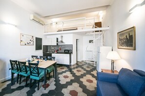 A compact living space with a dining area, kitchenette, and a sofa.