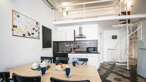 A modern kitchen with white cabinets, a black countertop, and a spiral staircase. - Nice Apartment Navona Square (Rome)