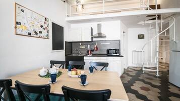 Una cucina moderna con mobili bianchi, un piano di lavoro nero e una scala a chiocciola.