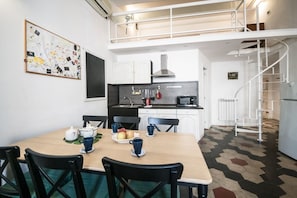 A modern kitchen with white cabinets, a black countertop, and a spiral staircase.