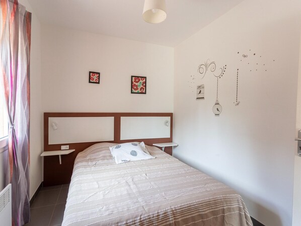 A bedroom with a bed, nightstands, a headboard, and wall decorations including framed pictures and wall art.