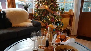 A cozy room with a Christmas tree, a dining table with food and drinks, and a sofa with a fluffy white throw. - Näset 4 Green Cabin in Småland with boat (Vena)