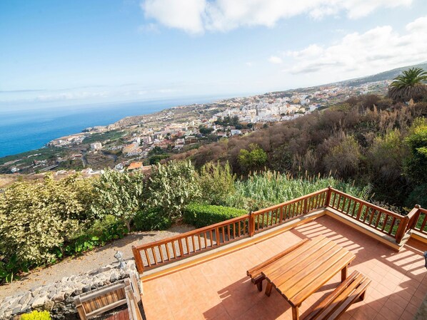 Una terraza con banco de madera con vistas a un pueblo costero.