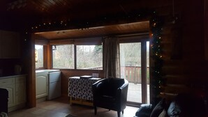 A cozy cabin interior with a kitchen, a dining area, and a large window overlooking a deck. - SNOWDONIA LOG CABIN RETREAT 4 BERTH FAMILY/PET FRIENDLY. STUNNING MOUNTAIN VIEWS (Trawsfynydd)
