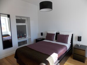 Een slaapkamer met een bed, nachtkastjes, een spiegel en een raam.
