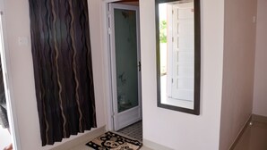 A hallway with a patterned curtain, a glass door with decorative elements, and a mirror on the wall. - Malompek (Padang)