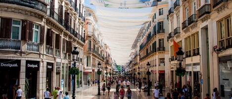 A pedestrian street lined with multi-story buildings, featuring storefronts and balconies.
