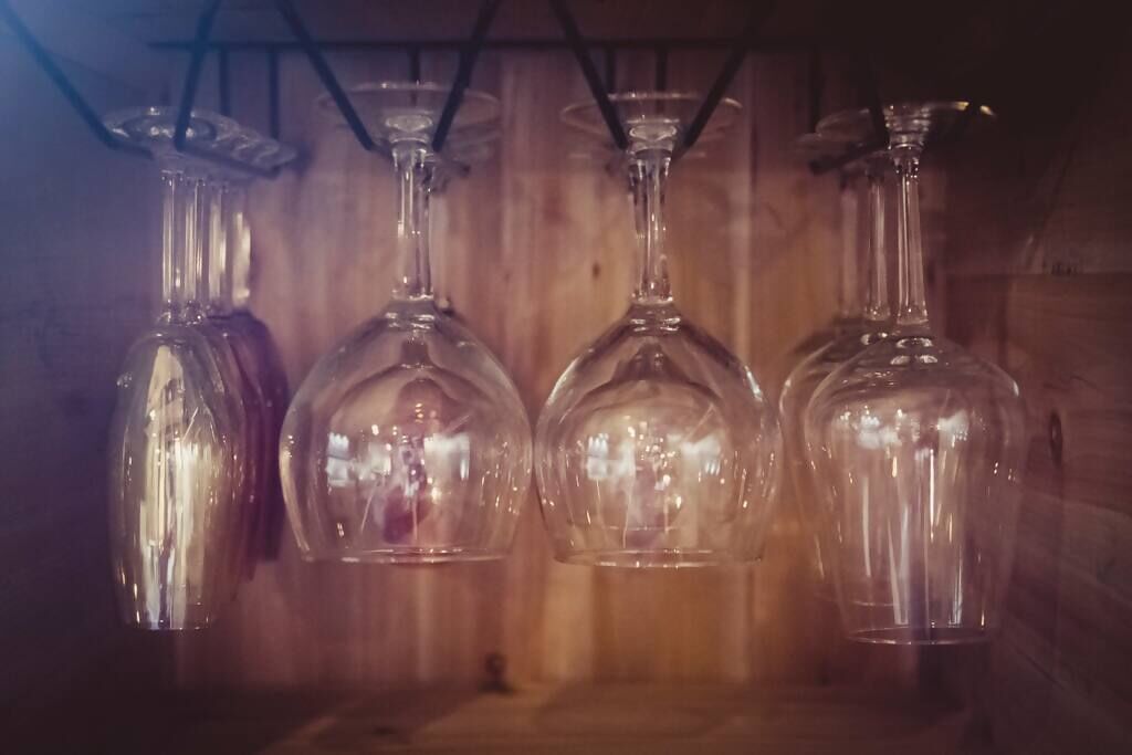 Cuatro botellas de vidrio transparente colgadas en un estante de madera.