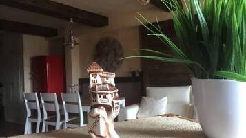 A dining table with a ceramic house figurine, a potted plant, and a clock on the wall.