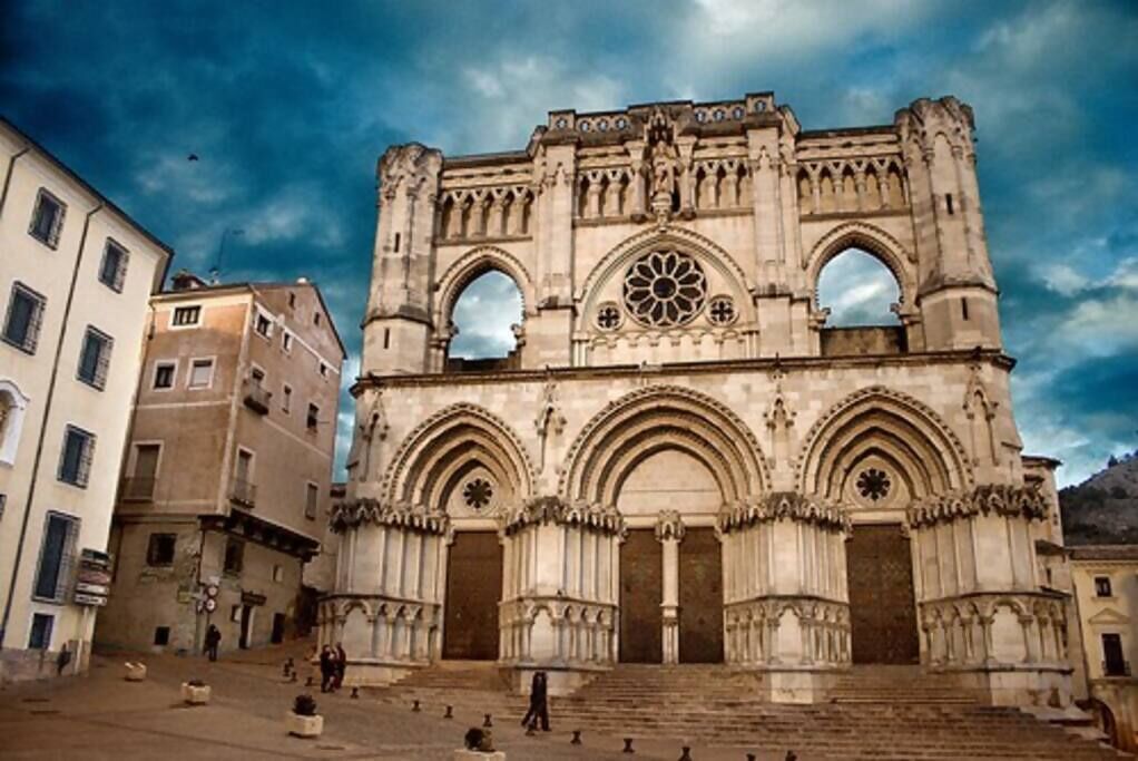 A historic cathedral with three large arches and a central rose window.