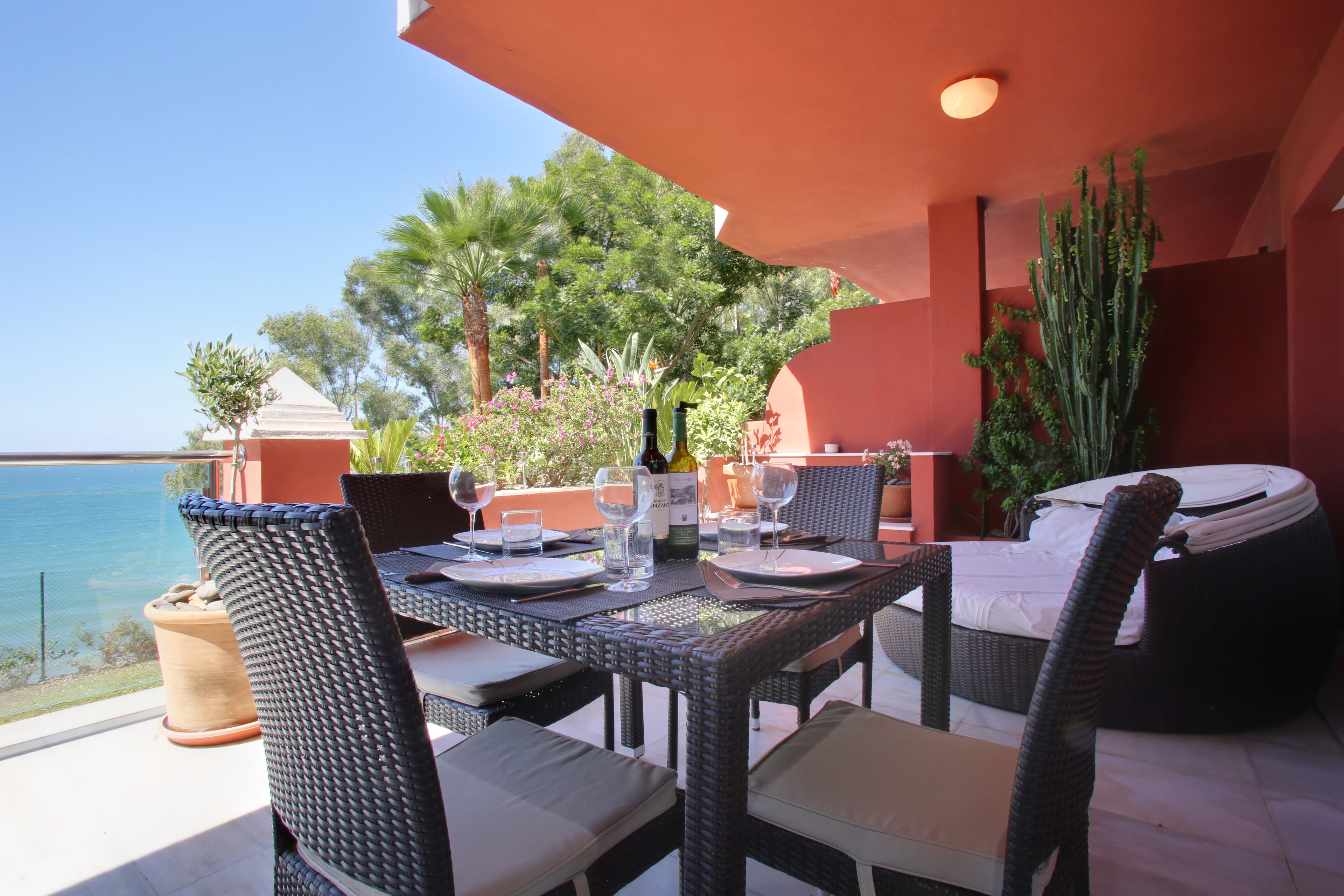 A dining area with a table set for two, overlooking a scenic view of the sea.