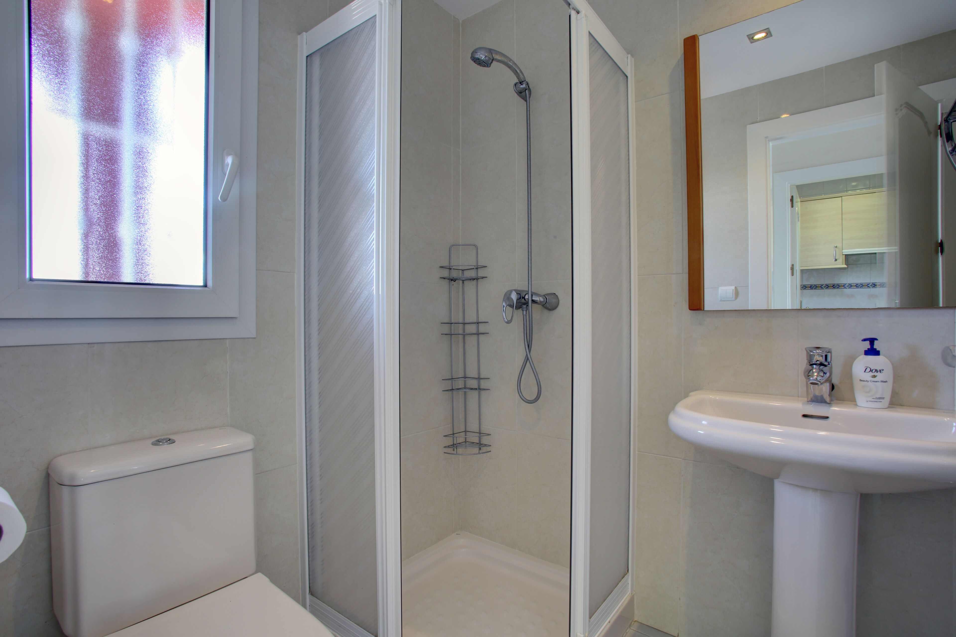 A bathroom with a toilet, a shower with a glass door, and a sink with a mirror above it.