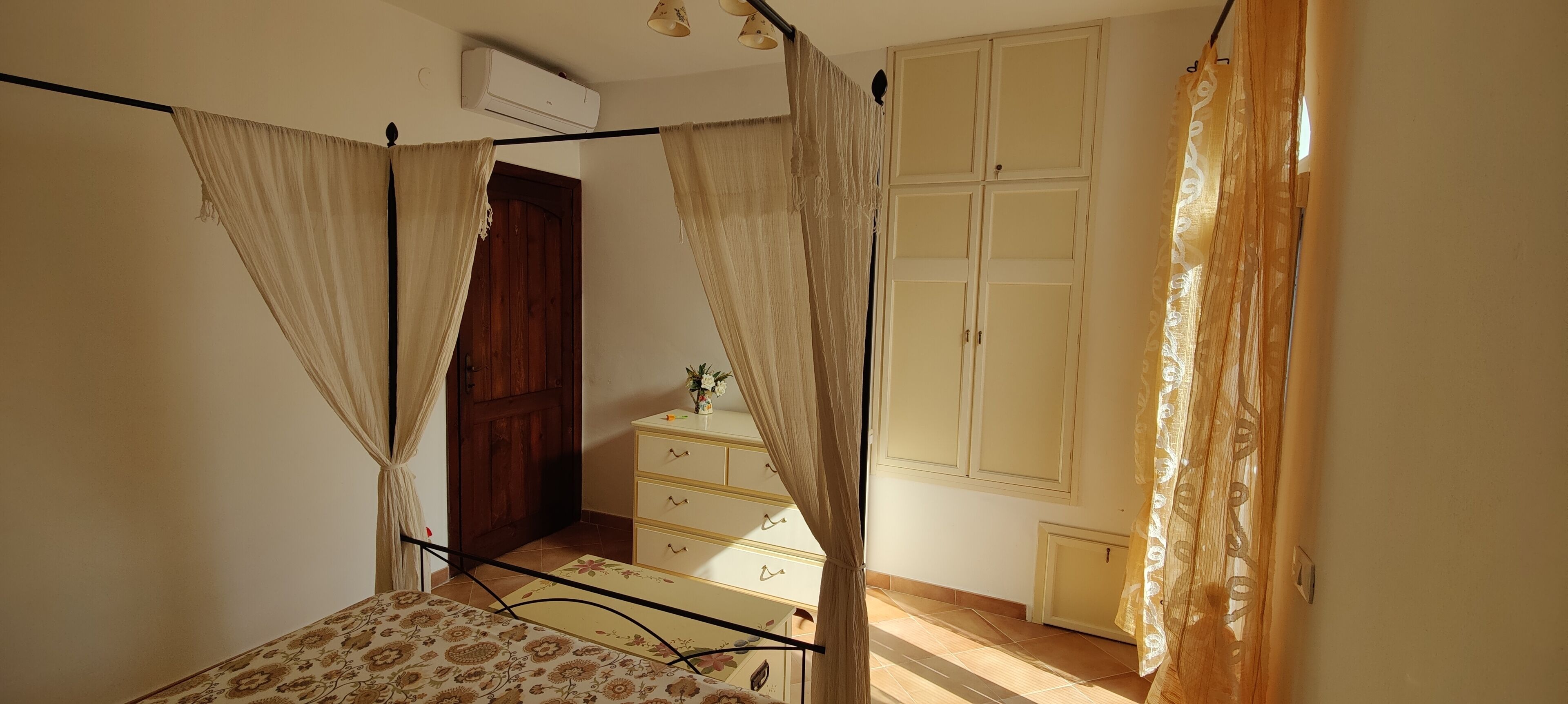 A bedroom with a bed, a dresser, a wardrobe, and a curtain.