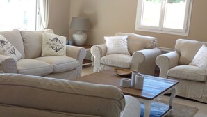 A living room with a beige sofa set, a wooden coffee table, and a lamp on a side table.