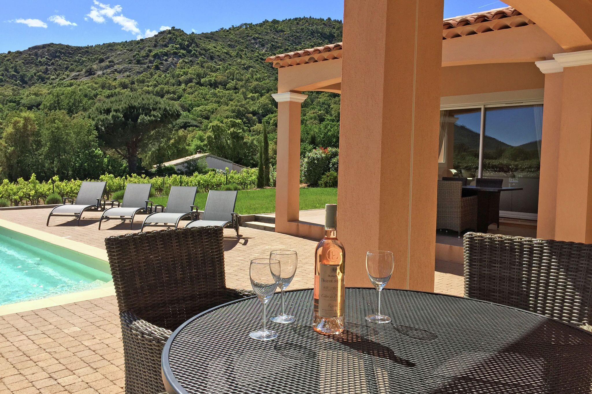 Une terrasse dotée de meubles en osier, une piscine et une vue imprenable sur les montagnes.