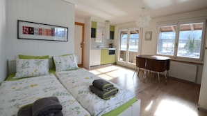 Ein Schlafzimmer mit Bett, Esstisch und Küchenzeile.