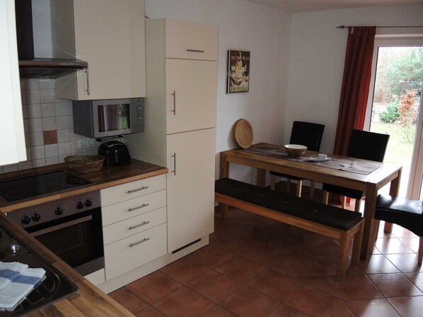 A compact kitchen with a microwave, oven, and a dining area with a table and chairs.