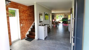 Un vestíbulo amplio con pared de ladrillo, armarios blancos y una escalera que conduce a otro nivel.
