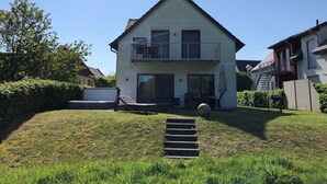 Una casa de dos pisos con un balcón, una puerta principal y un pequeño patio.