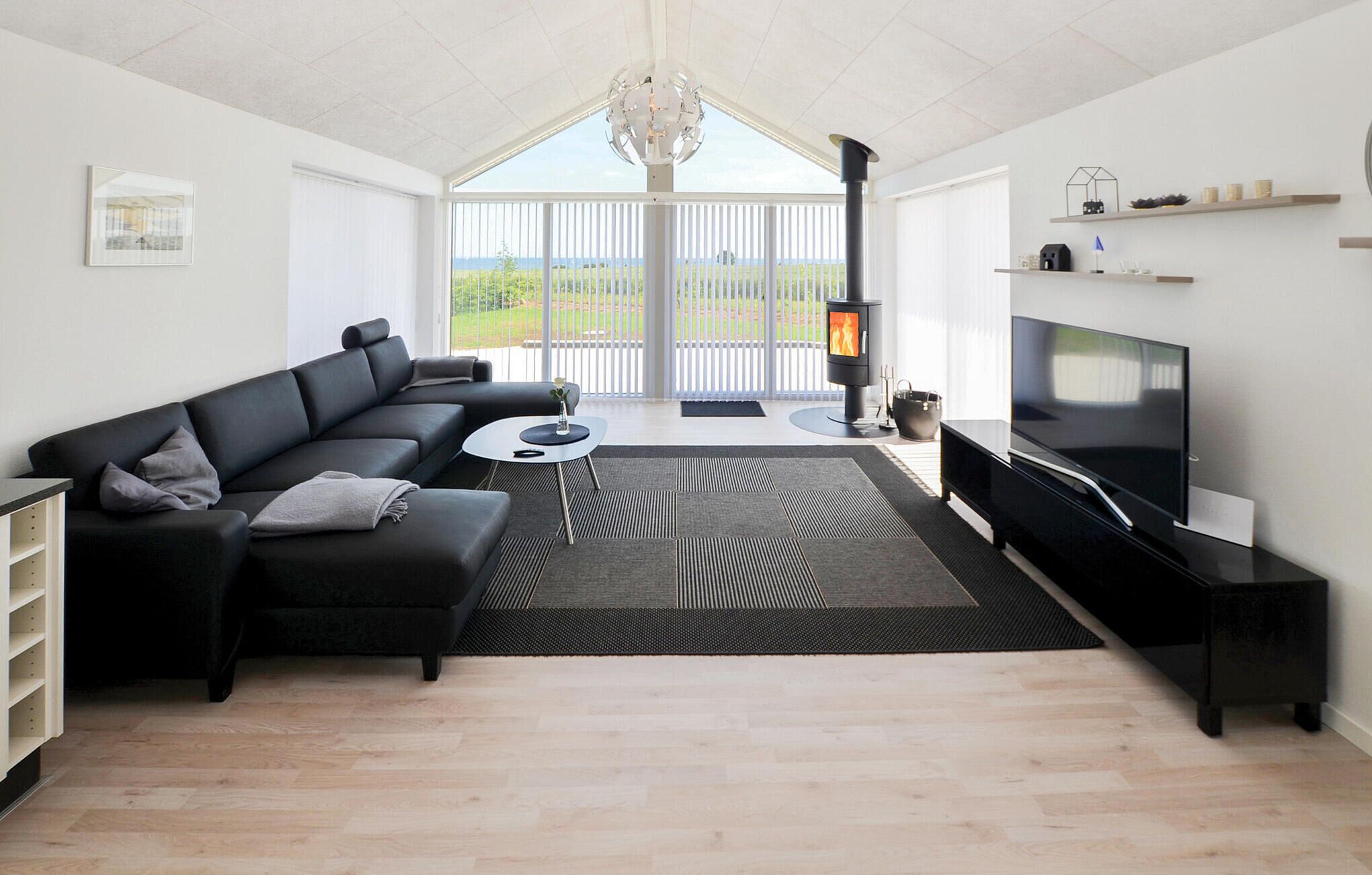 A modern living room with a black sofa, a round coffee table, a flat-screen TV, and a fireplace.