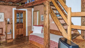 A rustic room with a wooden bed, a television, and a staircase. - schoenes Ferienhaus-Grossklein (Grossklein)