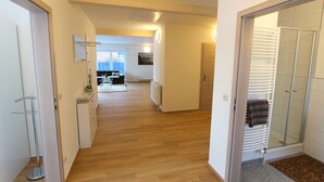 A hallway with wooden flooring leading to a kitchen area with a dining table and chairs. - Villa SEE-RESIDENZ - VILLA SEE-RESIDENZ (Malchow)