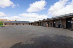 A motel with a large parking lot, multiple rooms with individual entrances, and a covered outdoor seating area.