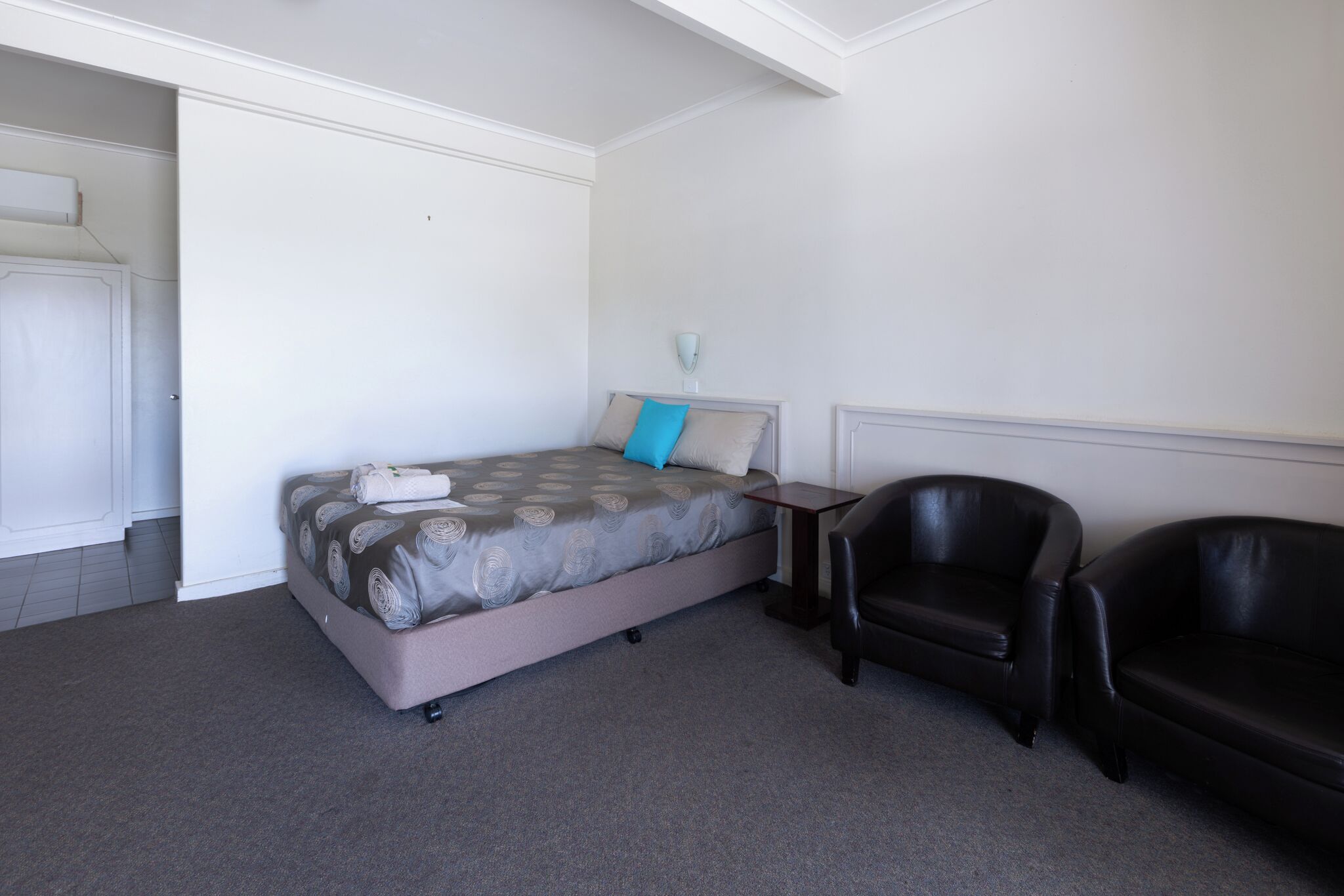 Un dormitorio con una cama, una silla y una mesita de noche.