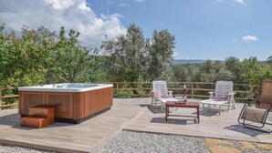 Eine Dachterrasse mit Whirlpool, Sitzgelegenheiten im Freien und Blick auf die umliegende Landschaft.
