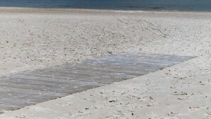 Une plage avec une promenade en bois qui mène à l’eau.