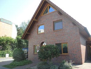Un bâtiment à deux étages, construit en briques, avec un toit à pignon, un petit porche et une enseigne portant le numéro « 27 ».