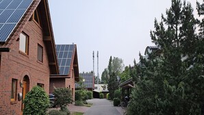 Un bâtiment en briques doté de panneaux solaires, un chemin pavé et une rangée d’arbres à feuilles persistantes.
