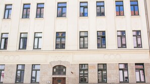 Un immeuble à étages doté d’une façade symétrique, avec des fenêtres régulièrement espacées et une entrée centrale avec une porte.