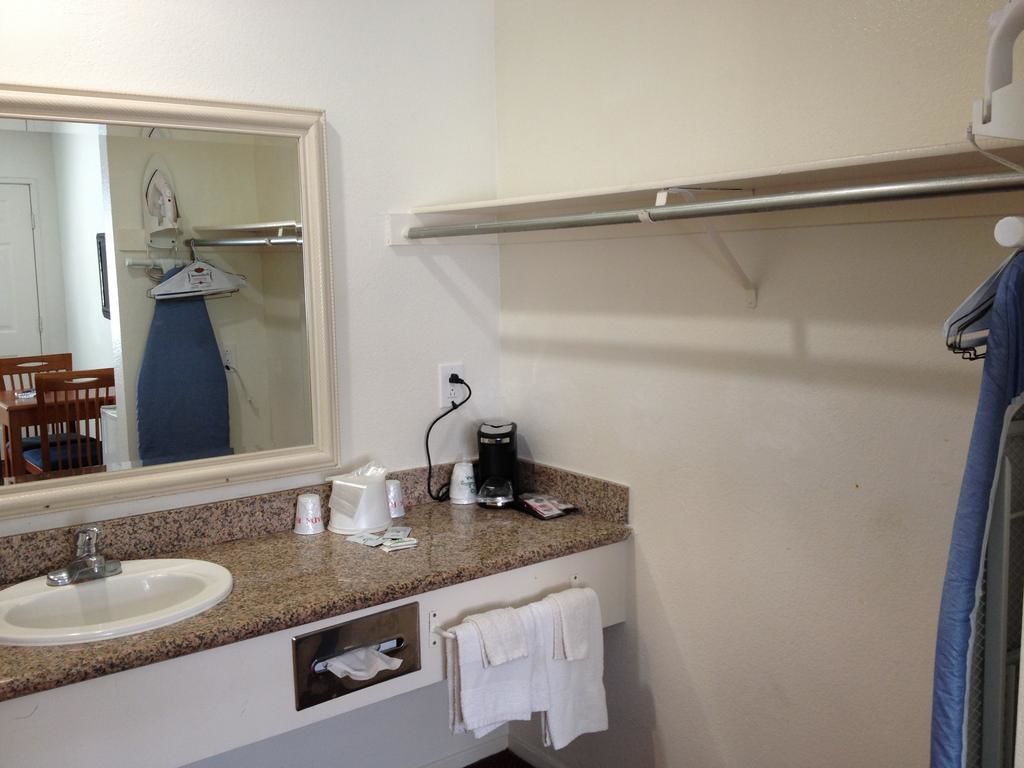 A bathroom with a sink, mirror, towel rack, and a shower curtain.