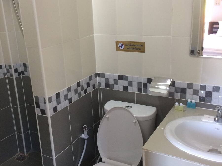 A bathroom with a toilet, bidet, and sink. There is a sign on the wall and a mirror above the sink.