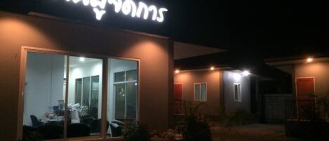 A modern building with a large illuminated sign, large windows, and a well-lit entrance area.