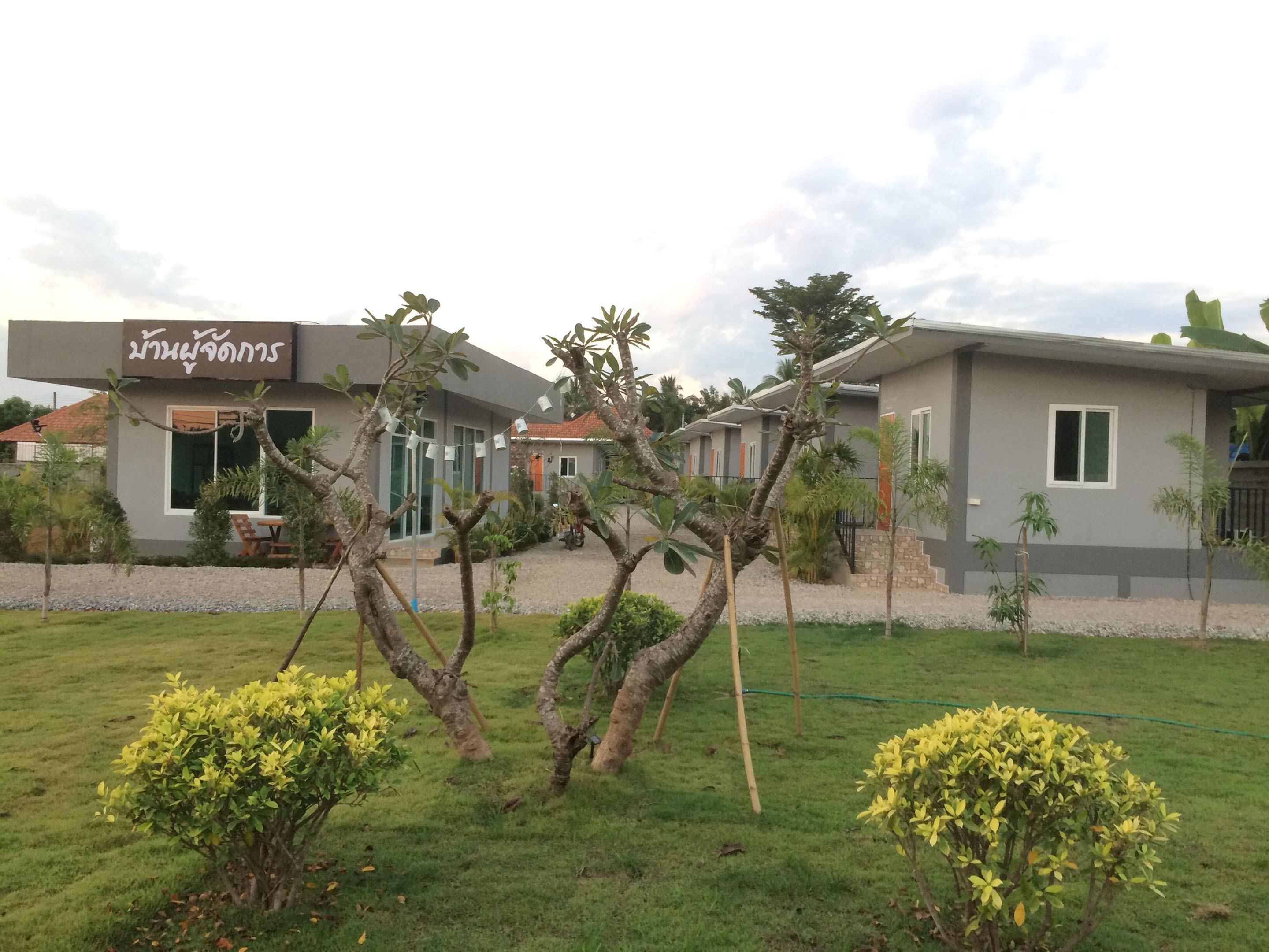 A modern building with a sign in a foreign language, surrounded by well-maintained grass and small trees.